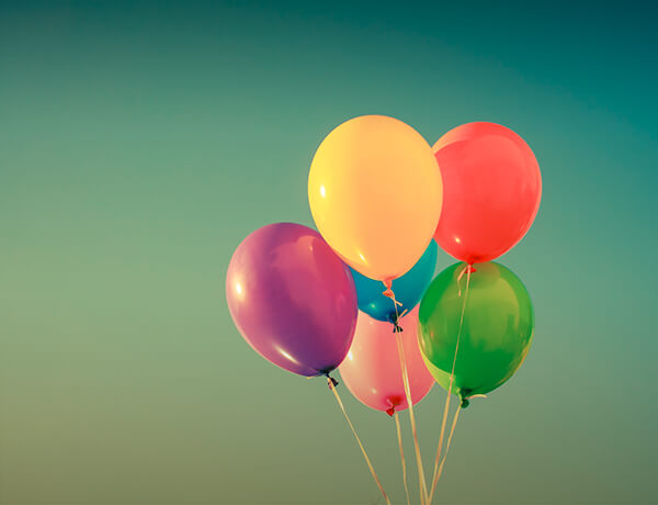 five multi colored balloons float on strings