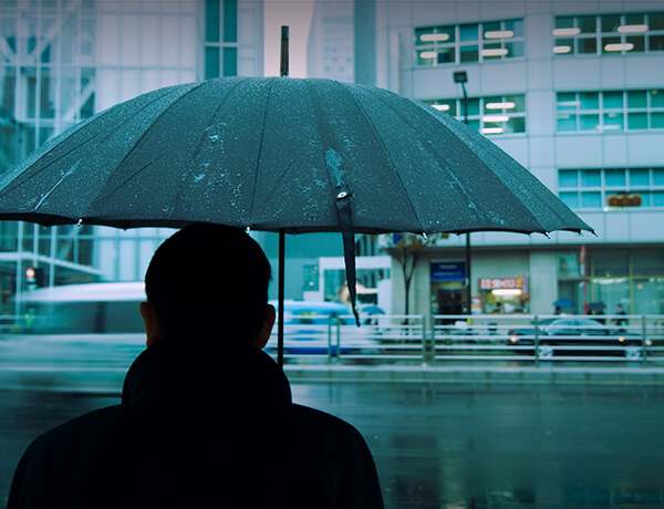 Man standing in rain with umbrella open