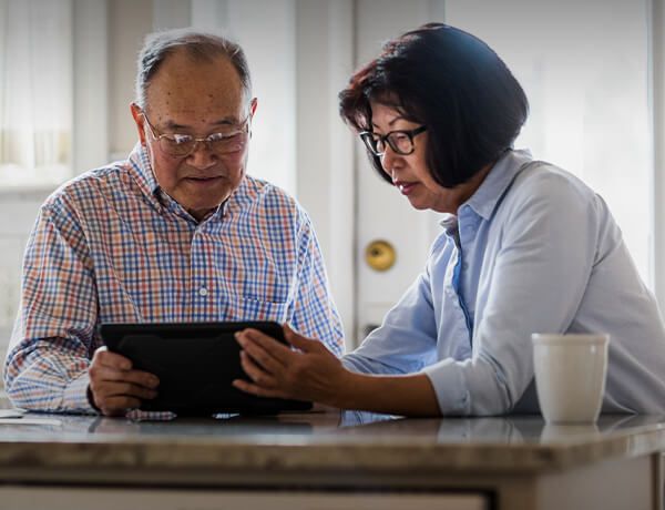 Older couple holds tablet around kitchen table
