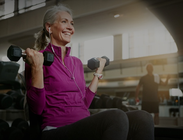 Woman of retirement age does arm curls at the gym