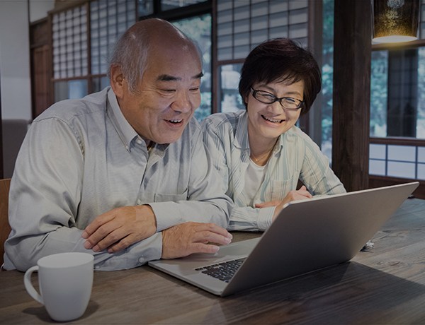 Older man and women smile looking at a laptop